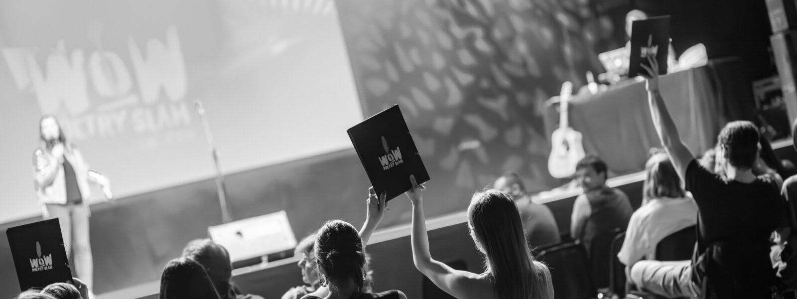 Publikum stimmt mit Wertungskarten bei einem WoW Poetry Slam NRW über die Auftritte der Slam Poet:innen ab